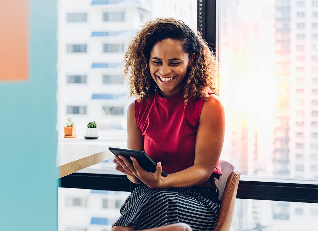 Report a Claim - Happy Woman Sitting with her Tablet to Report a Claim to the Insurance Company