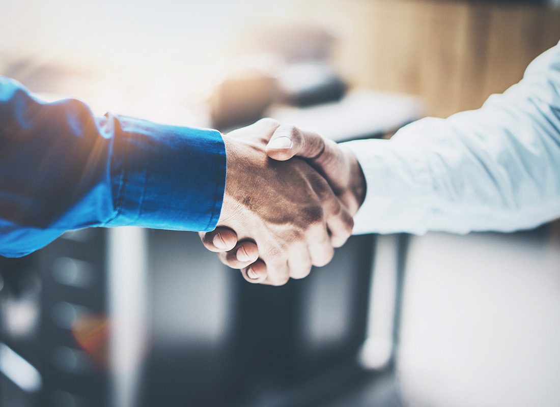 Elements Insurance Clients - Closeup View of Arms of Two Businessmen Shaking Hands in the Office to Celebrate Partnership